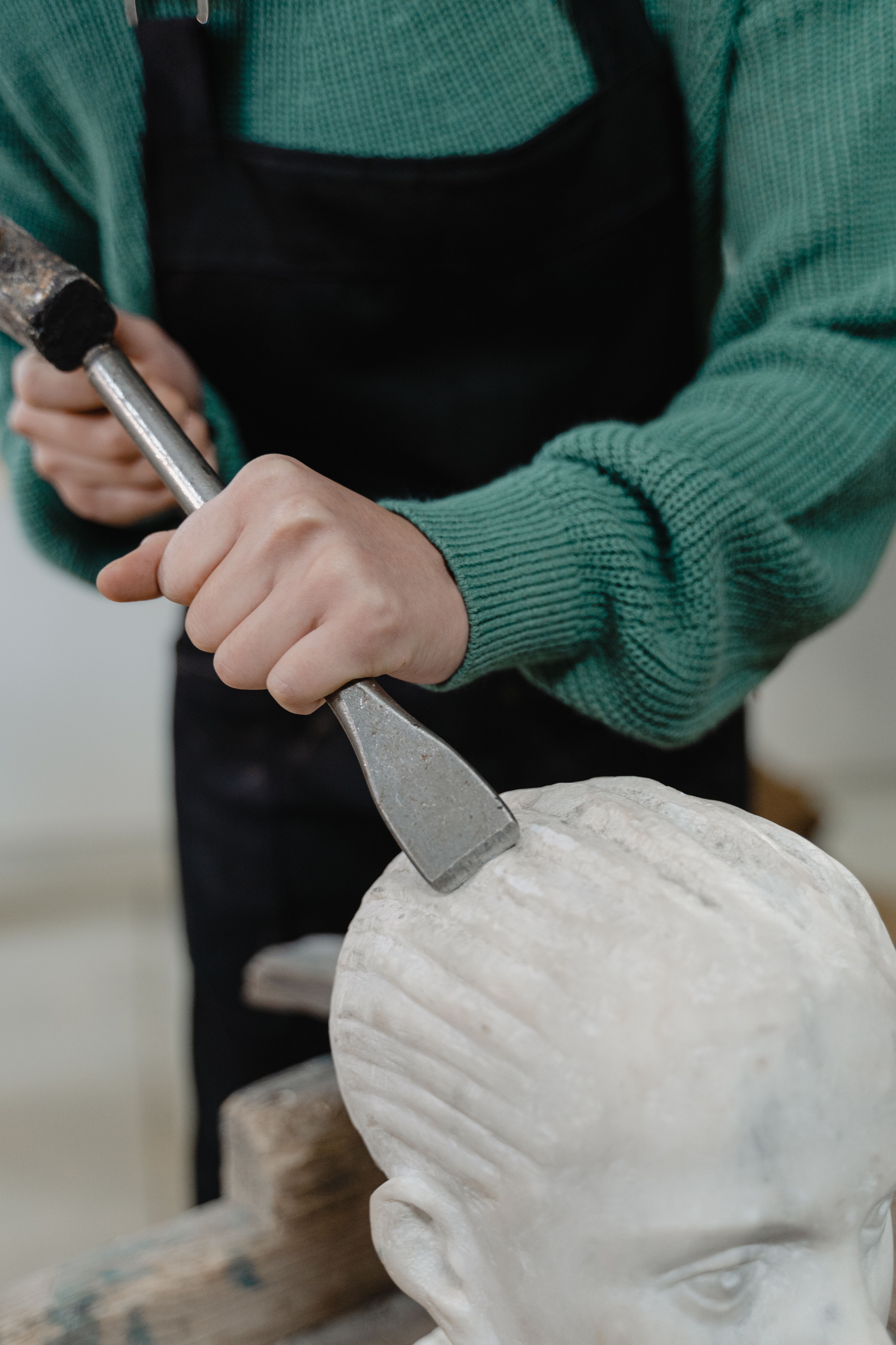 A person using a hammer and chisel on stone