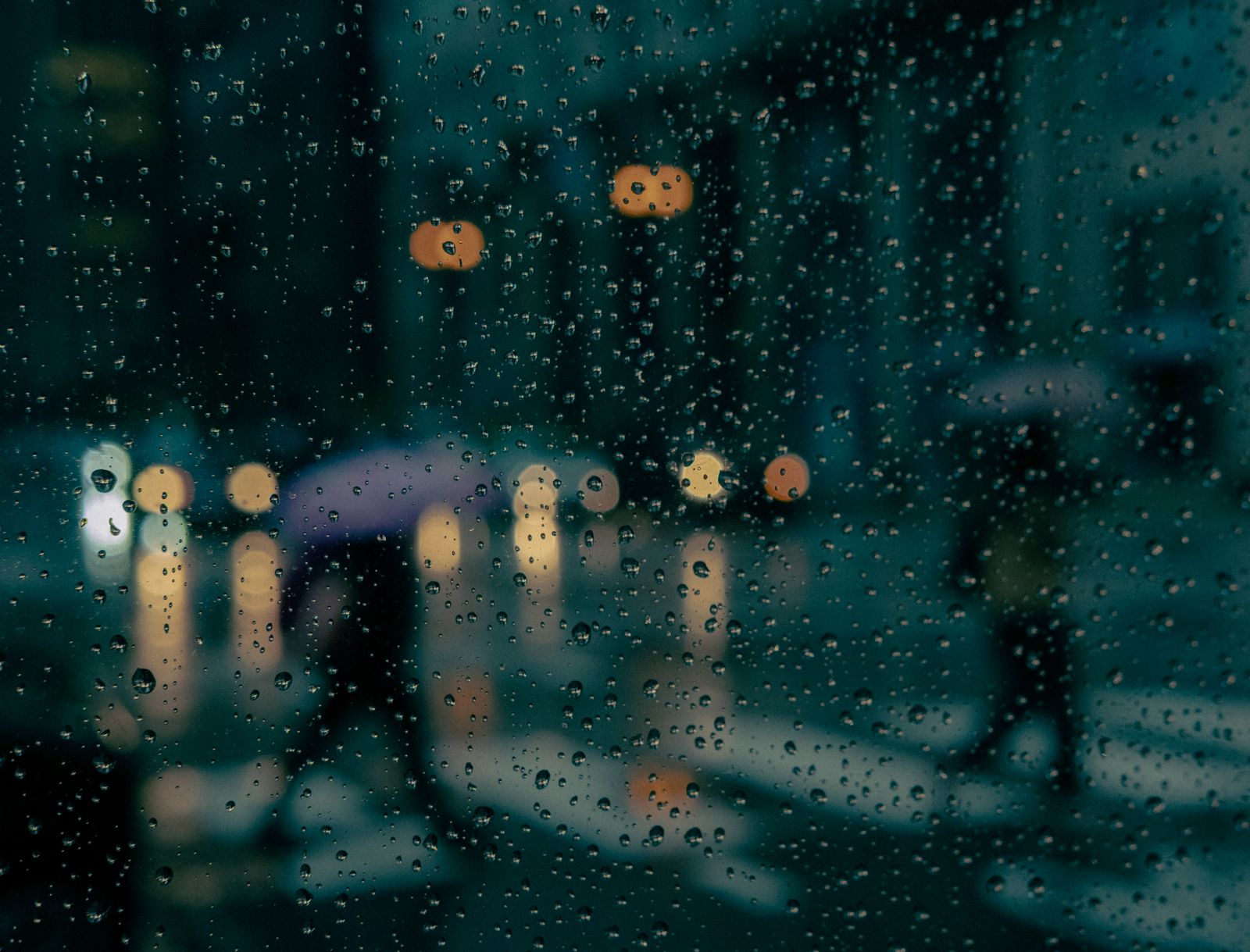 Rain on a window at night with blurred city lights