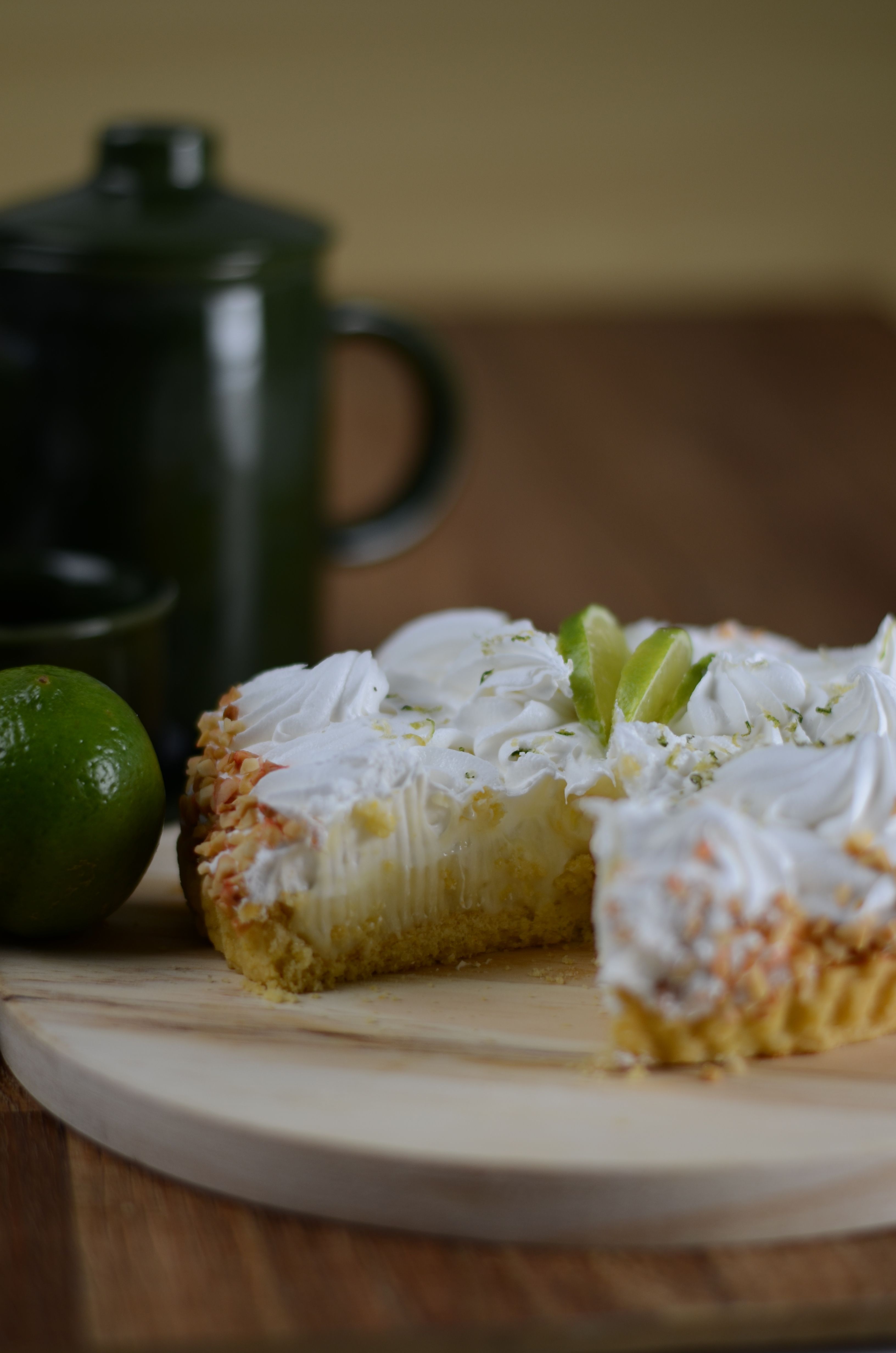 A key lime pie with whipped cream on a wooden board