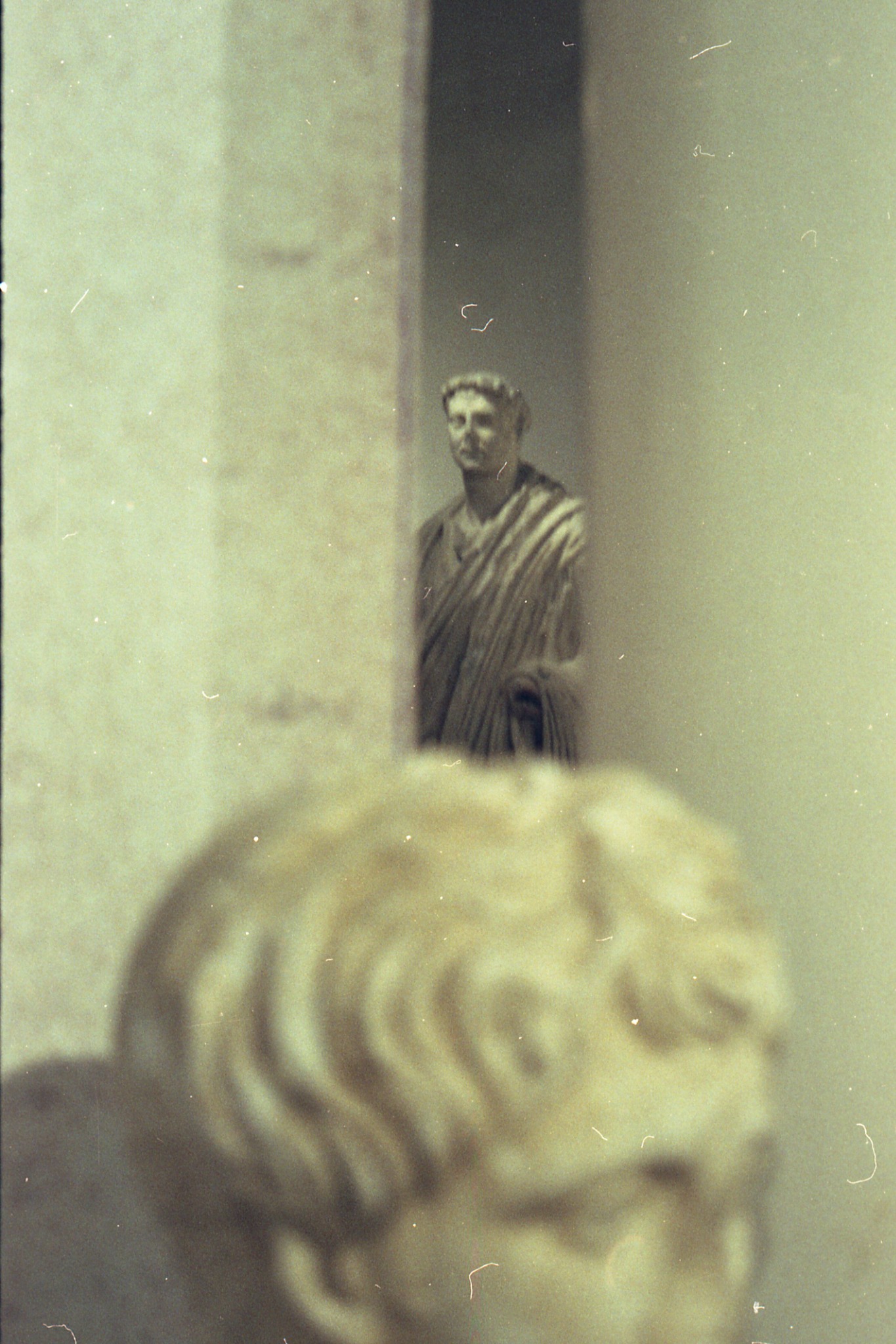 Two marble statues seen through a soft, grainy museum view
